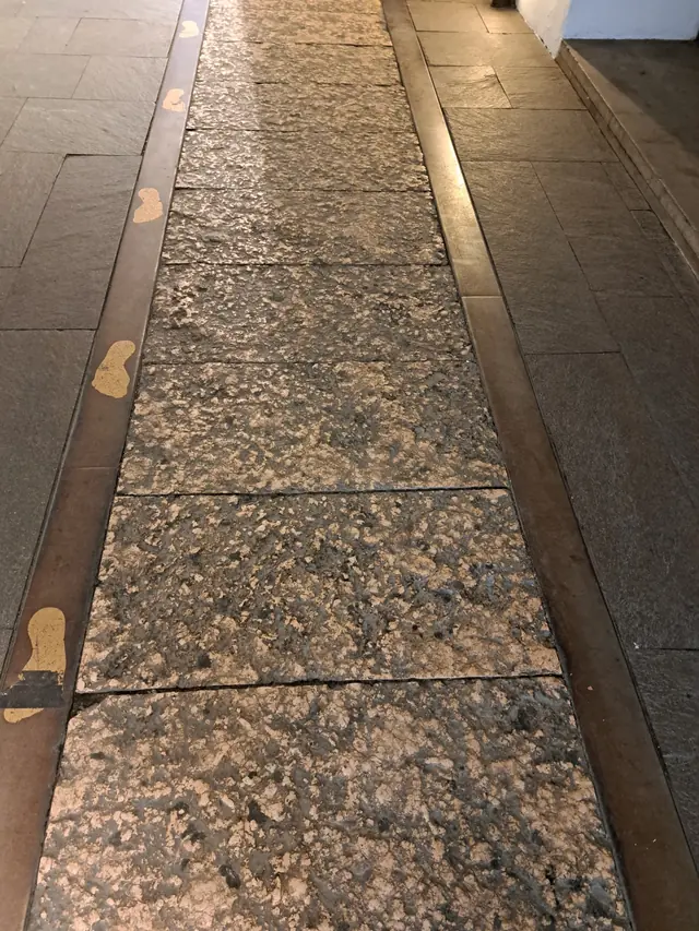 Stone walkway under the arcades, blackened with dirt